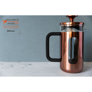 Copper French press coffee maker on a marble surface with a gray background
