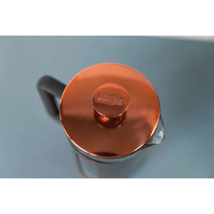 Copper lid of a French press with 'La Cafetiere' branding on a light blue background